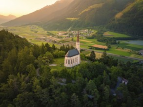View from a hill with a church over a wide valley at sunset