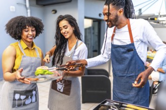 Happy multi ethnic friends preparing grilled vegetables and meat, enjoying barbecue party on the