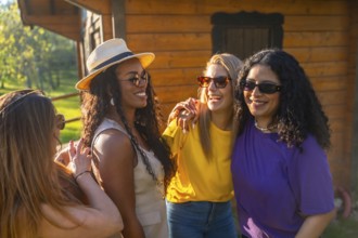 Four multi ethnic female friends enjoying a sunny day, wearing sunglasses and laughing together