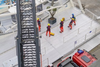 Several firefighters stand on a platform next to a crane jib, fire brigade exercise for gondola