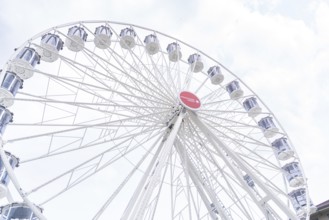 Large Ferris wheel with white gondolas and a sunny sky as a backdrop, Ferris wheel construction,