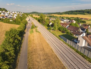View of a railway line winding through a rural village and agricultural fields, construction of the