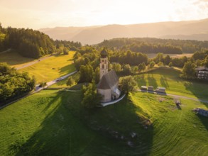Church in a gentle hilly landscape with rich greenery and warm sunset light