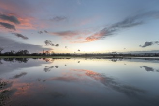 De ondergang van de zon kleurt de lucht in prachtige tinten, terwijl het meer de reflectie van de