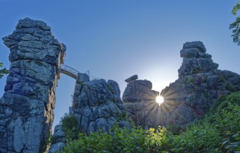The morning sun shines through an opening in the Externsteine. The Externsteine, a sandstone rock