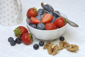 Bowl with blueberries and strawberries, walnut