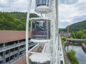 Ferris wheel with gondolas next to a building and a river, Ferris wheel construction for the 950th