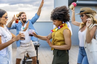 Cheerful friends dancing and enjoying drinks at a rooftop party, celebrating friendship and good