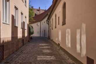 Old town, alley, historic buildings, facades, windows, light reflection, cobblestones, blue sky,