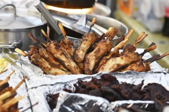Grilled Thai chicken skewers on display at street food market. Traditional gai yang with wooden