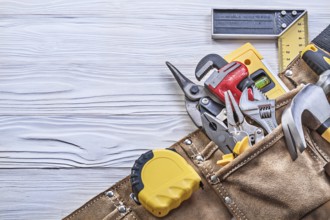 Construction of tools in a tool belt on a wooden board Construction concept