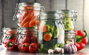 Jars with marinated food and organic raw vegetables