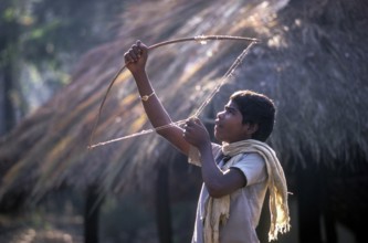 Jenu Kurumba tribal boy aiming with a stone, Nagarahole, Karnataka, South India, India, Asia