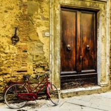 Red bicycle leaning against a wall in Pienza