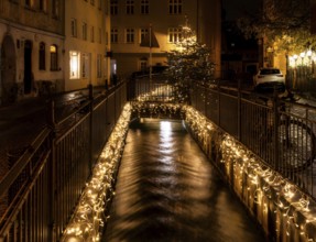 Canal with flowing water in Augsburg decoreated with chrismas lights