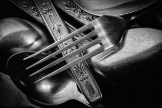Abstract black and white photo of mixed silver forks, spoons and knives