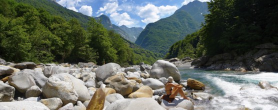 young lady sunbathing by a rocky alpine foothills stream in the remote valley of Val Verzasca, near