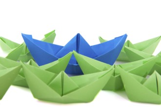 Gren paper boats with one blue ship
