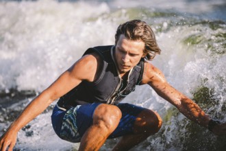 A man is surfing on a surfboard drawn by a motor boat above the wave of the boat. Weixerfer is