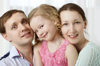 Portrait of happy family. Young parents with cute little daughter. Girl looking shy