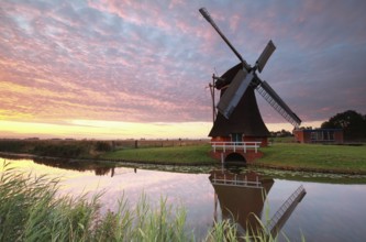 Dutch windmill by river at sunrise, Netherlands