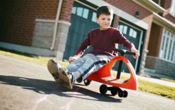 Small boy is having fun riding his toy on the street, Toronto, Canada