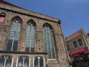 Large brick building with high pointed arch windows and clear blue sky, Bruges, Belgium