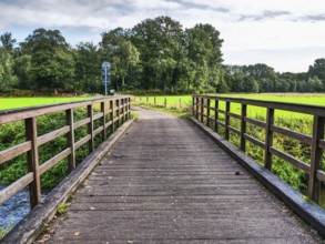 A wooden bridge leads over a river and offers a beautiful view of the surrounding area, vreden,