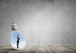 Businesswoman inside of light bulb in empty concrete room