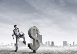Determined banker man against modern cityscape breaking dollar cement figure