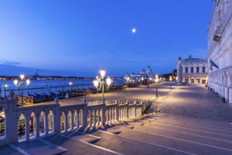 Bridge over a canal, blue hour, moon behind over the church Maria della Salute, Venice, Veneto,