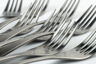 Abstract artistic photo of place setting, being eight reclining forks against a white background