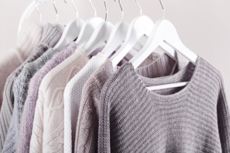Warm knitted, autumn, winter clothes hanging on a rack, trending concept, pastel colours