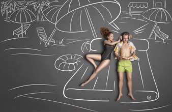 Love story concept of a romantic couple lying on an air mattress against chalk drawings background.
