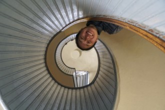 Woman looking down on the top a spiral staircase, circular architectural shape, San Diego,