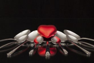 Nine spoons and red heart on a black glass desk
