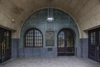 Arched entrance with decorative tiles and an information board, entrance to the St. Pauli Elbe