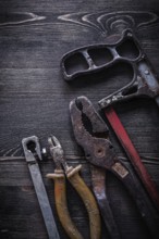 Rusty vintage hacksaw nippers pliers on wooden board construction concept