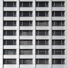 Front view of the facade of a modern commercial building with geometric repeating windows and grey