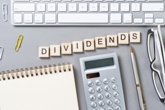 Dividends payment concept with letters on wooden cubes. Still life of office workplace with