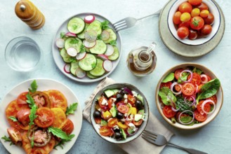 Fresh vegetarian salads, overhead flat lay shot of an assortment. Variety of plates and bowls with
