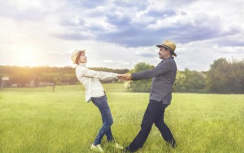 A portrait of a happy middle-aged couple holding hands in the green field