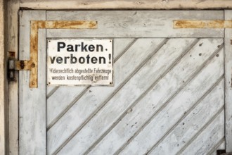 An image of a private no parking sign with german text Illegally parked vehicles will be towed at