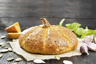 Pumpkin bread on paper, garlic, basil, pieces and seeds of a vegetable on the background of a dark