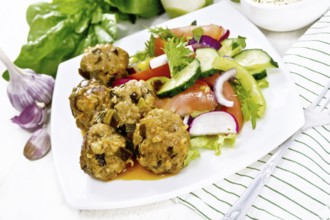 Minced meatballs with spinach, oatmeal and green onions in tomato sauce, vegetable salad in a