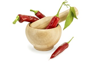Three fresh chilli pepper with a green leaf in a wooden bowl and a pepper on the table isolated on