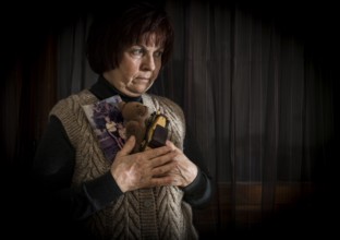 Senior woman hold pictures of childrens. Toys