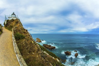 The white building of the lighthouse looks spectacular on a high cape. New Zealand. Nugget Point