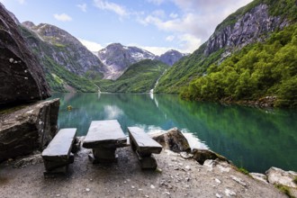 Cozy tourist wooden table and benches on the shore. Picturesque mountain lake Bondhuswatnet.