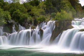 A large waterfall flowing powerfully through trees and rocks, Krka National Park, Krka Waterfalls,